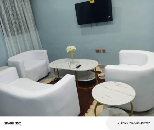 a room with white chairs and a table and a tv at Itele guest house in Itele