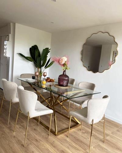 une salle à manger avec une table en verre et des chaises blanches dans l'établissement T3 Haut standing, à Saint-Raphaël