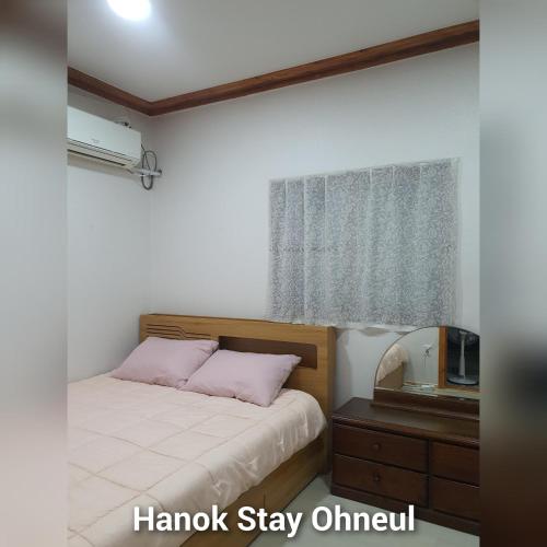 a bedroom with a bed with pink pillows and a window at Hanok Stay Ohneul in Gyeongju