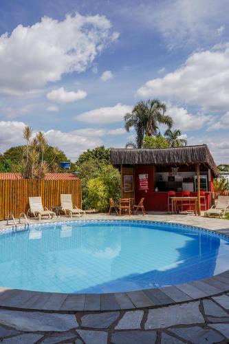 a large swimming pool with chairs and a building at Pousada Ikabana in Pirenópolis