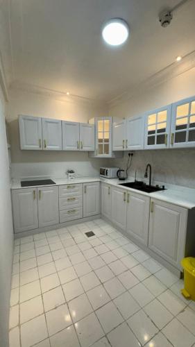 Una cocina blanca con gabinetes blancos y un fregadero. en عجمان كورنيش, en Ajman