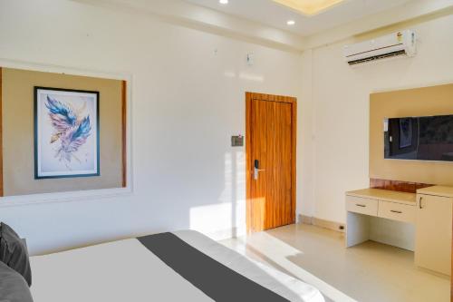 a white bedroom with a bed and a tv at Hotel O Chouksey Farmstead in Bhopal