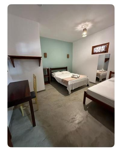 a bedroom with two beds and a table and a desk at Vila Lua Aparts - Apartamento 2 in Jericoacoara