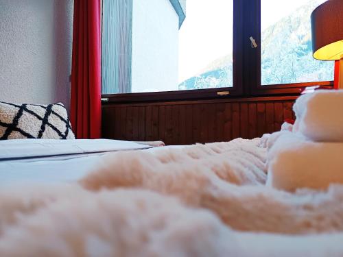 - un lit dans une chambre avec 2 fenêtres dans l'établissement Chamonix : Studio intime au bord du lac des Gaillands et pistes de ski, à Chamonix-Mont-Blanc