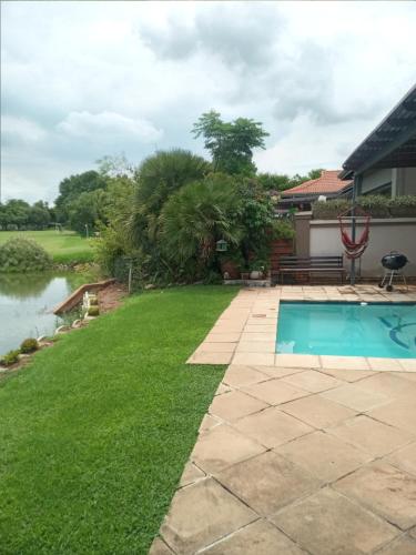 a backyard with a swimming pool and green grass at Pecanwood Estate Cosy home 3 bedrooms with pool in Hartbeespoort