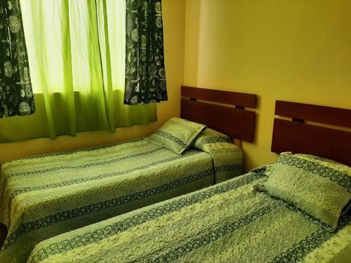 zwei Einzelbetten in einem Zimmer mit grünen Vorhängen in der Unterkunft Departamento portal del mar in La Serena