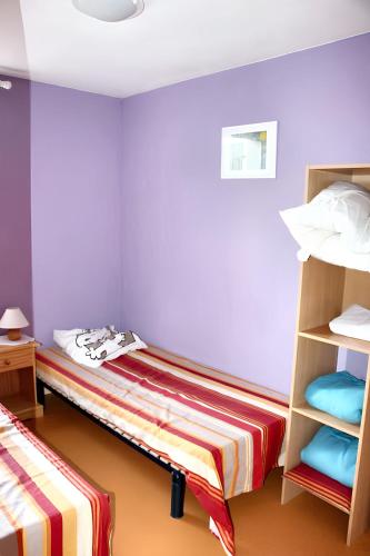 deux lits dans une chambre aux murs violets dans l'établissement Maison accueillante à Calvisson avec piscine et terrasse, à Calvisson