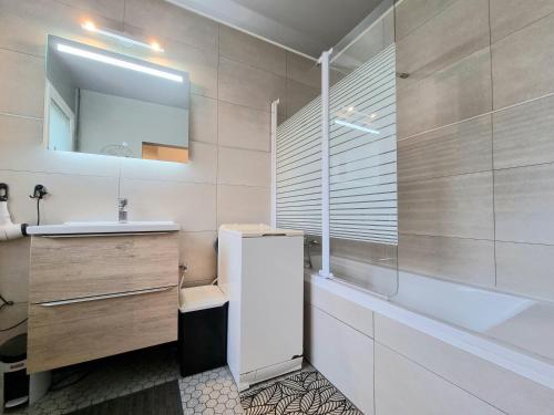 une salle de bain avec un lavabo, une baignoire et un miroir dans l'établissement Maison tout confort avec jardin, à 1km de la plage, à Saint-Hilaire-de-Riez