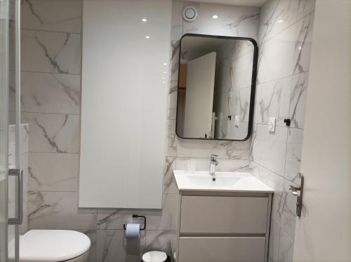 ein weißes Badezimmer mit Waschbecken und Spiegel in der Unterkunft Iris Garden Cottage in Saint-Germain-en-Laye