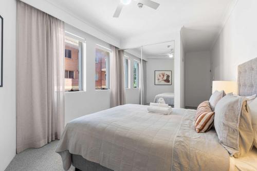 a white bedroom with a large bed and a window at Camperdown Cozy Corner 1 in Sydney