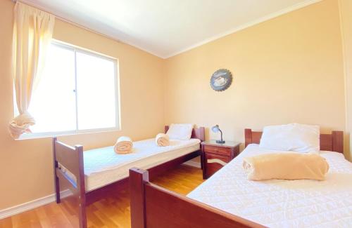 two beds in a room with a window at Bella casa en Los Molles Nº3 a 8 min de la playa in Los Molles
