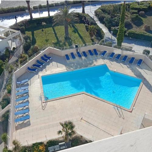 une vue aérienne d'une grande piscine avec des chaises longues bleues dans l'établissement Canigou by the sea, à Canet