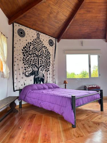 a bedroom with a purple bed and a tree mural at Casa Ganesha Lago Puelo in Lago Puelo