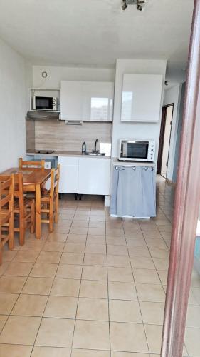 - une cuisine et une salle à manger avec des placards blancs et une table dans l'établissement Appartement cosy Canet-en-Roussillon 25 m² vue sur le lac, à Canet