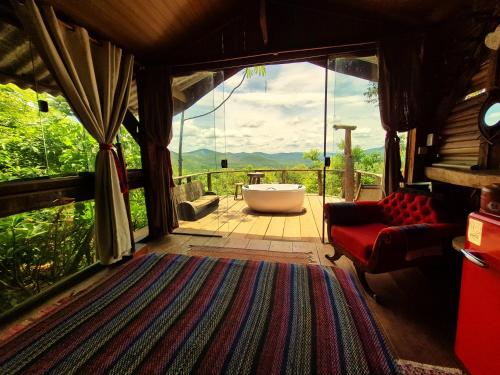 a living room with a tub and a large window at Ecopousada Toca do Guará in Alto Paraíso de Goiás