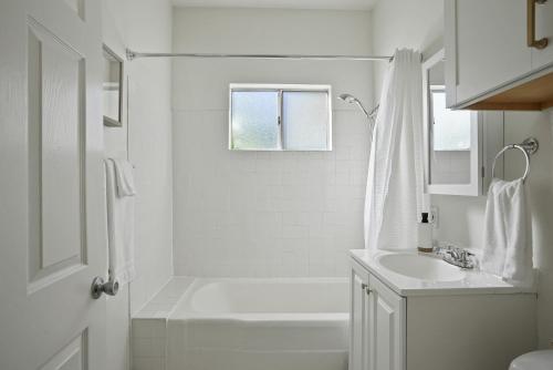a white bathroom with a shower and a sink at Draper Bungalow By CoastVH - Charming 1940 in San Diego