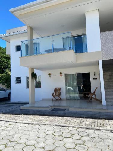 a white house with two chairs in front of it at Casa Temporada Praia do Mutá in Porto Seguro