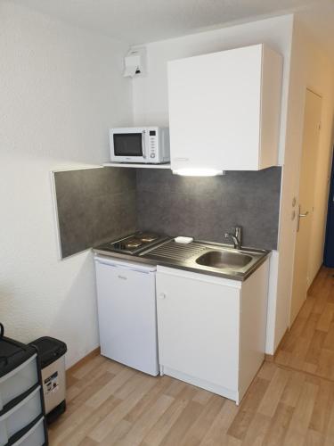 une petite cuisine avec un évier et un micro-ondes dans l'établissement Studio meublé centre ville Paray le Monial 116, à Paray-le-Monial