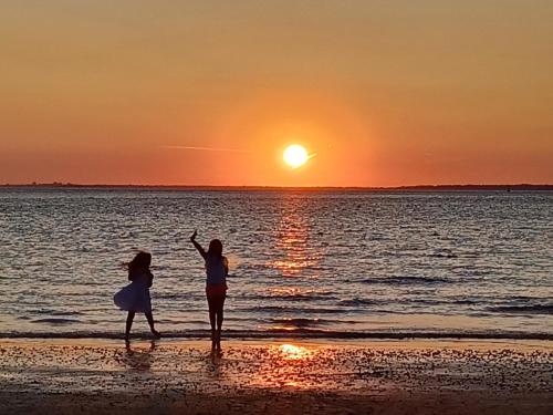 two women standing on the beach at sunset at Brambles Chine 209 Self Catering Holiday Home Colwell Bay Isle of Wight - Ferry Offers in Freshwater