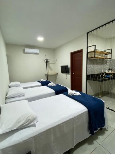a room with three beds with blue and white sheets at Pousada Solare Home in São Miguel do Gostoso