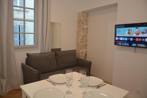 a dining room table with wine glasses and a couch at Maison Jacob - Hyper centre - Maison historique - Air conditioning - Wifi in Avignon