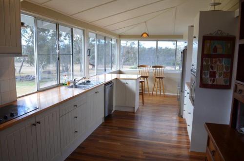 a kitchen with white cabinets and windows and a wooden floor at Seagoe Homestead in Stanthorpe