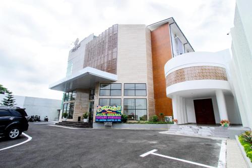a building with a car parked in a parking lot at Hotel Sepanak by Amazing in Curup