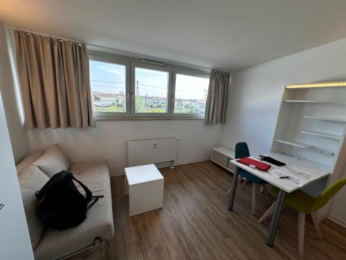 una pequeña sala de estar con escritorio y sofá en Appartement superbe, en Núremberg