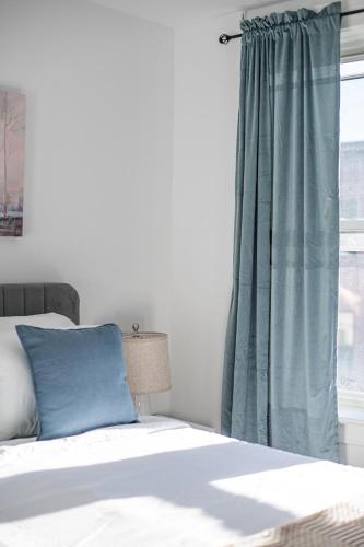a bed with a blue pillow and a window at The Mirage Stay 3 Bedroom Apt 20 Min to NYC in West New York