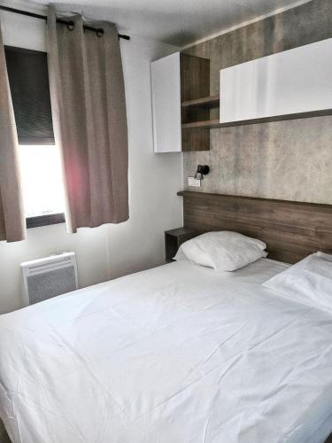 une chambre avec un lit blanc et une fenêtre dans l'établissement Bungalow cosy à Canet-en-Roussillon avec piscine partagée, à Canet