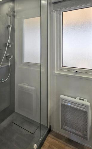 d'une douche avec une porte en verre et une fenêtre. dans l'établissement Bungalow cosy à Canet-en-Roussillon avec piscine partagée, à Canet