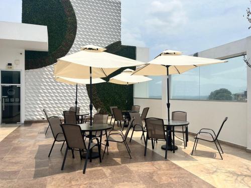 a patio with tables and chairs with umbrellas at River View Suites Guayaquil in Guayaquil