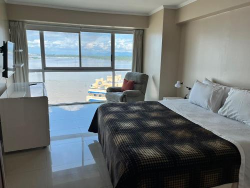 a bedroom with a bed and a chair and a window at River View Suites Guayaquil in Guayaquil