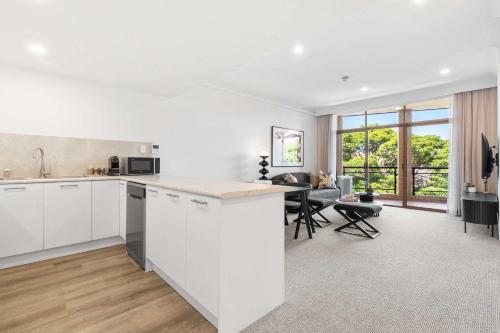 a kitchen with white cabinets and a dining room at Camperdown Cozy Corner 8 in Sydney