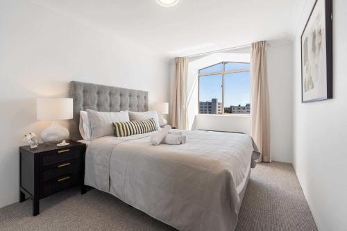 a white bedroom with a large bed with a window at Camperdown Cozy Corner 10 in Sydney