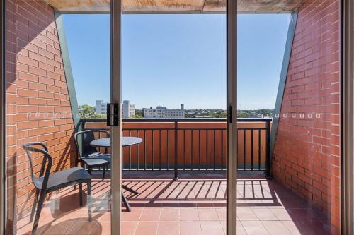 a balcony with a table and chairs on a brick wall at Camperdown Cozy Corner 10 in Sydney