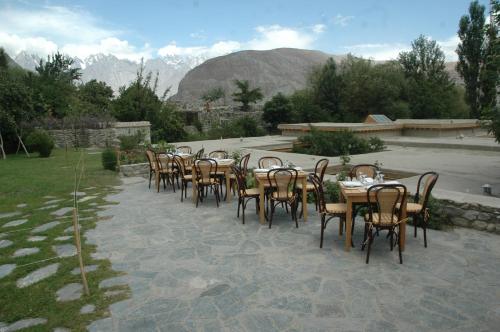 a row of tables and chairs with mountains in the background at Serena Khaplu Palace in Khaplu