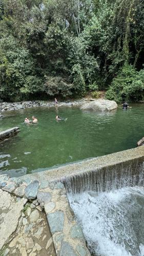 a group of people swimming in a pond with a waterfall at Hotel Restaurante LA AZOTEA in El Cerrito