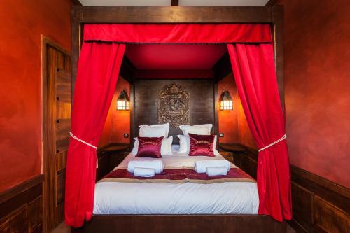 a bedroom with a canopy bed with red curtains at Hôtel Cap Pirate in Cap d'Agde