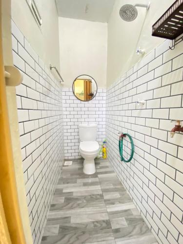 een badkamer met een toilet en witte metrotegels bij Homestay Tanjung Malim DMalim in TanjongMalim