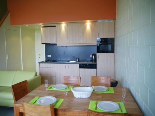 a kitchen with a wooden table with plates and chairs at Apartment in Groede near the Beach in Groede