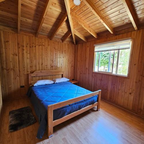 1 dormitorio con 1 cama en una cabaña de madera en Cabañas Los Arrayanes, en Licán Ray