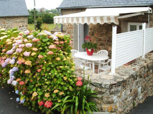 a garden with a table and flowers on a stone wall at Terraced House in Lanmodez near Sandy Beaches in Lanmodez