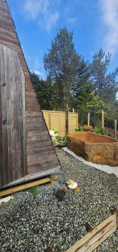 a wooden barn sitting on top of a gravel yard at Glamping DESEO con Jacuzzi, Wifi, fogata y vistas de Medellín in Santa Elena