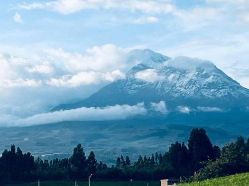 a snow covered mountain with clouds in front of it at Quinta Los Ángeles in Riobamba