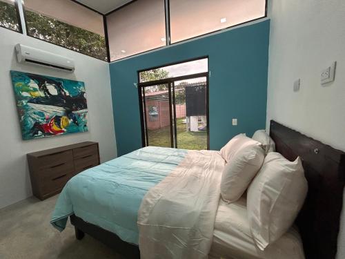 a bedroom with a bed with blue walls and a window at Bravo paraiso azul beach house in Savegre