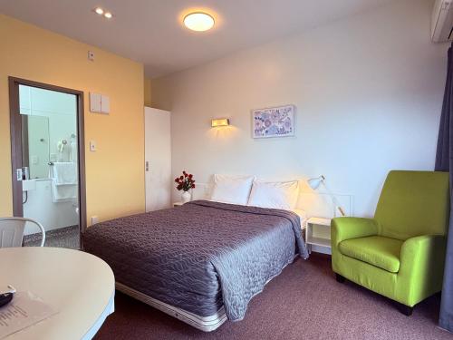a hotel room with a bed and a green chair at Morrinsville Motel in Morrinsville