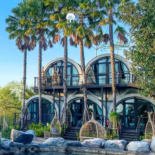 a building with palm trees in front of it at DAMNERNPAWA in Bang Khon Thi