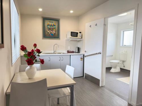 a small kitchen with a table and a vase with flowers at Morrinsville Motel in Morrinsville