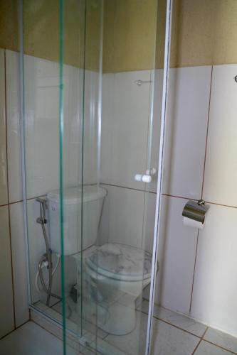 a bathroom with a toilet and a glass shower at Pousada Villa Bella in Maricá